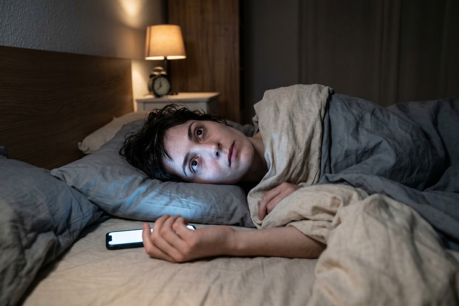 Person sitting at a desk late at night, surrounded by multiple glowing screens showing notifications