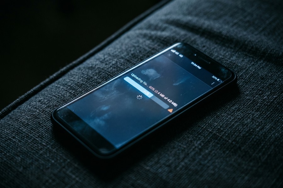 Hand holding smartphone with YouTube Studio upload screen showing podcast video episode metadata fields